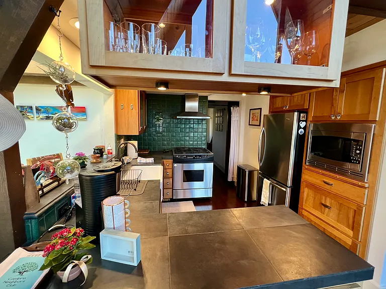 Thoughtful use of space with natural materials, standing at the kitchen island with the A-frame window reflected in the glass cabinets