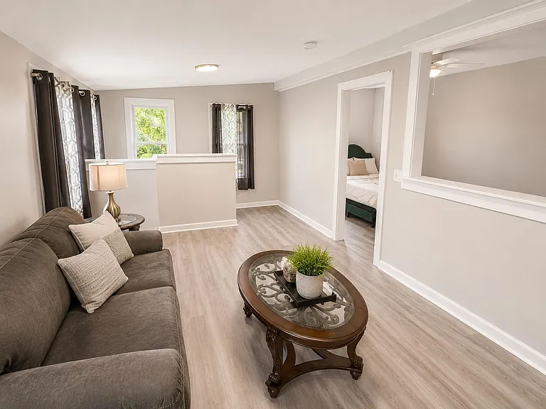Open sitting area with a sofa, coffee table, and large interior pass-through, plus nearby access to an adjacent bedroom.