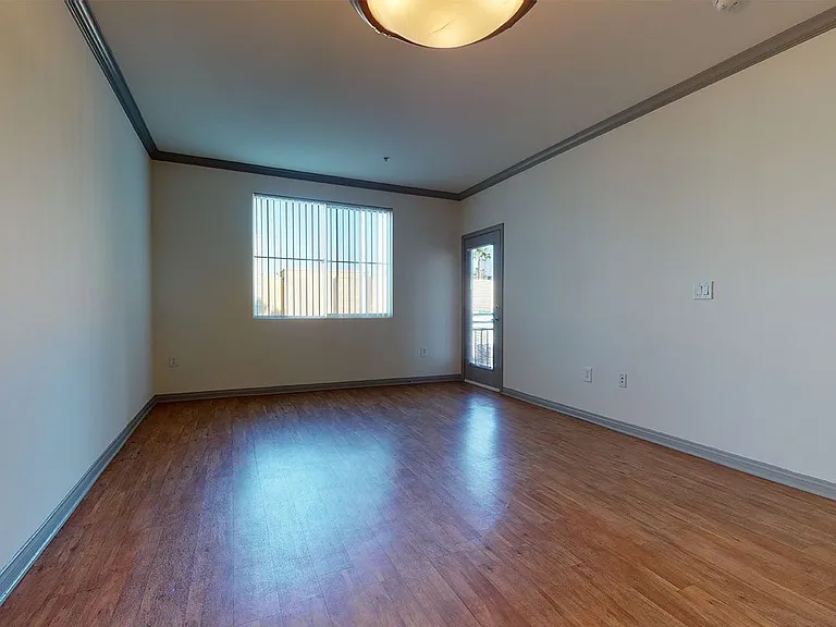 Apartment living room with wood-style flooring and patio or balcony in select homes.
