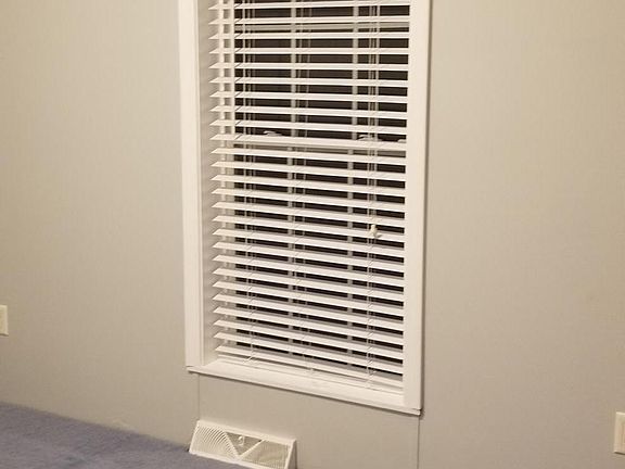 Small bedroom painted light gray with gray blue new carpet.