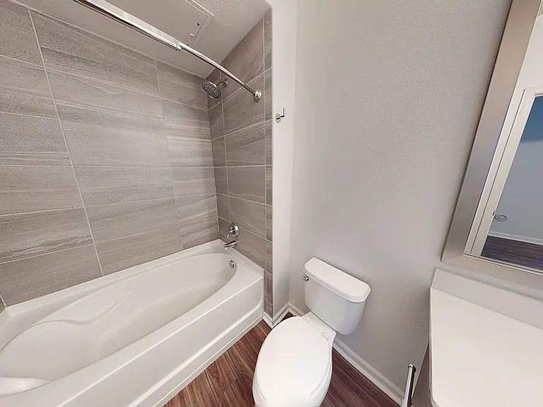 Apartment bathroom with large soaking tub and wood-style flooring.