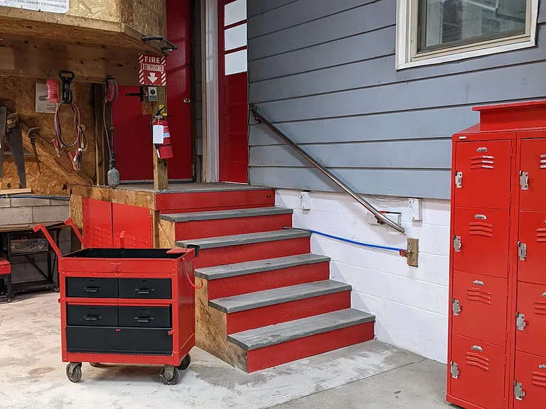 The solid red door goes to the storage area and the windowed red door goes to upper garage.