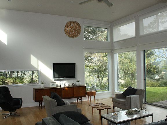 Living room with 13 ft. high ceilings. Sunshades on windows.