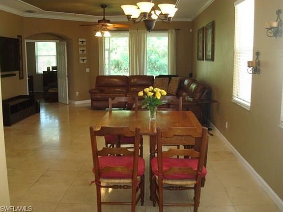 Showing off the eating area and great room with the Travertine floor tile, crown molding, view of pr