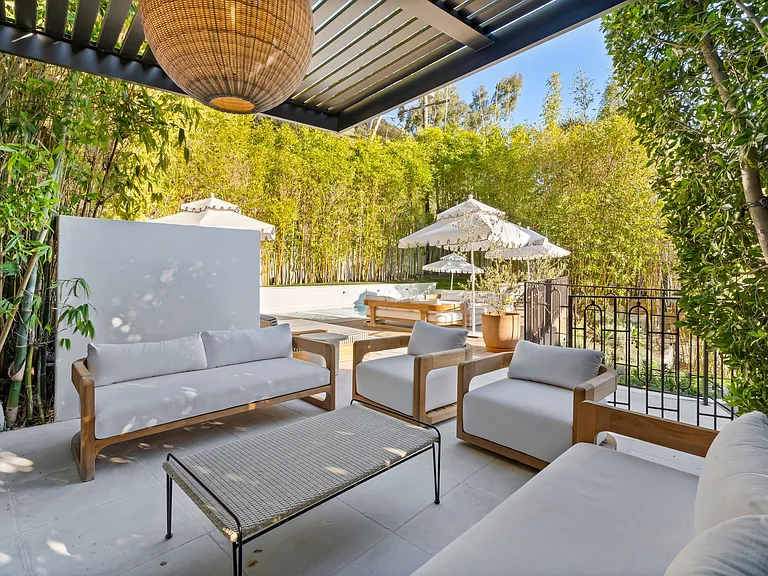 Sleek wood furniture, a shaded pergola, and everything you need for laid-back luxury.