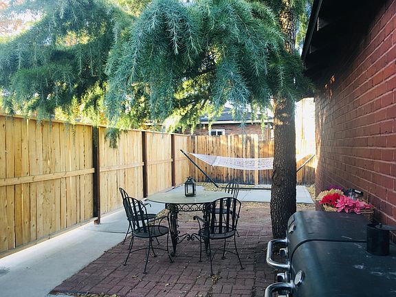 large fenced patio area with a shade tree