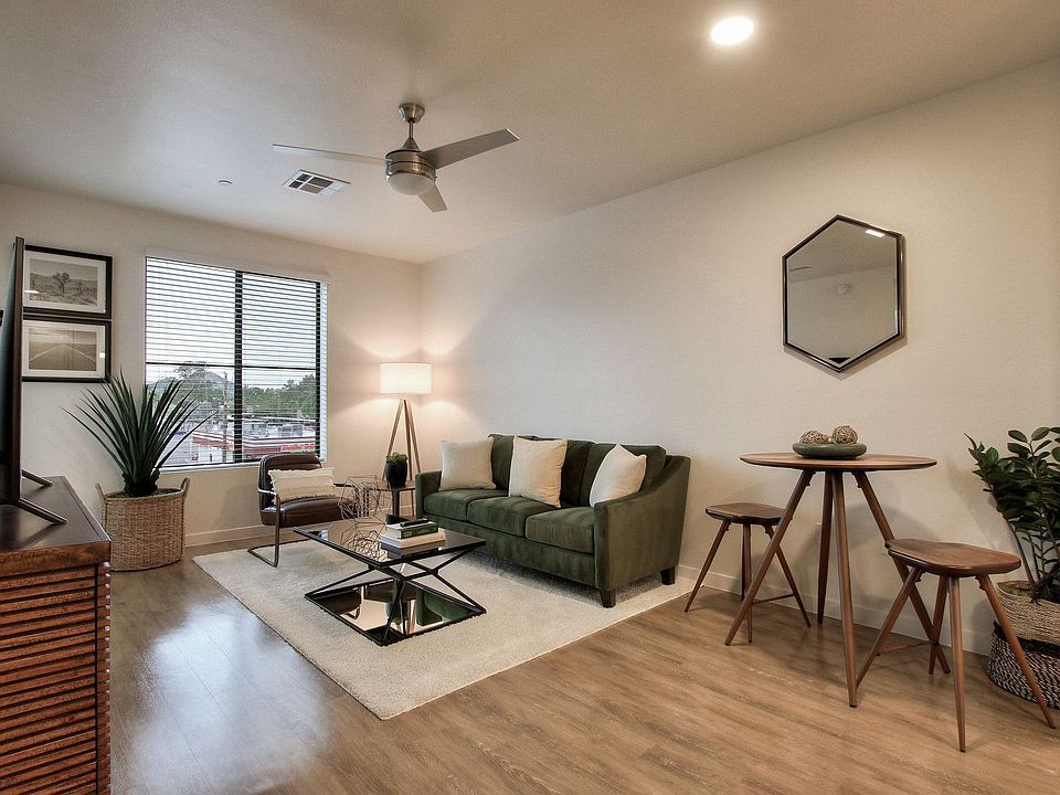 White living room with table, brown couch, modern ceiling fan, recessed lighting, and mountain view.