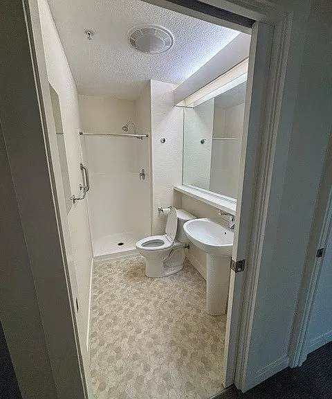Primary bathroom room with shower and pedestal sink.