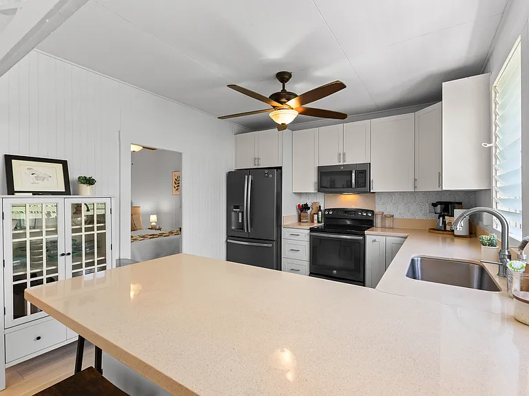 The kitchen is open to the living room and features plenty of storage and counter space, a ceiling fan, full size refrigerator with water station, oven, microwave and dishwasher. The kitchen is fully equipped.