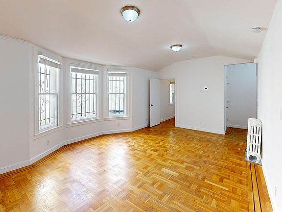 Sunlit room with a large window and a wood-like flooring