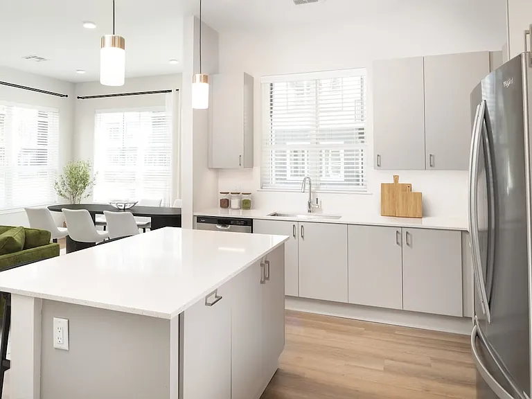 Base Collection kitchen with stainless steel appliances, white quartz countertops, white tile backsplash, grey cabinetry, and hard surface flooring