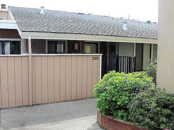 Front of the property has gated entrance and cozy patio area with storage.