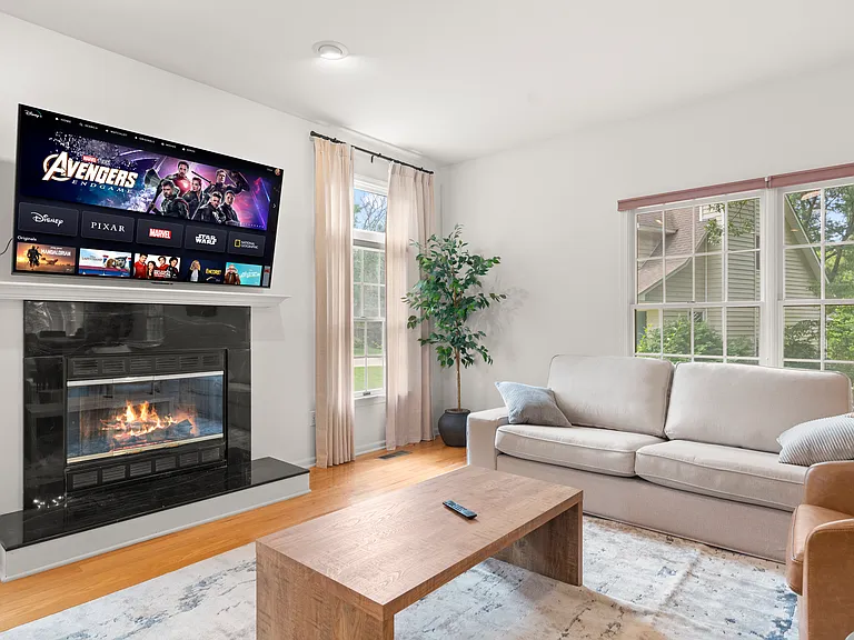 Inviting main living room with a cozy fireplace, comfortable furnishings, and large windows.