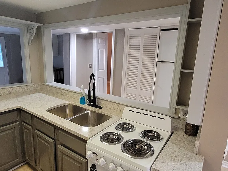 Picture of kitchen taken from kitchen doorway located in the back room (Rm #2), looking at front door in front room (Rm #1), and door to bedroom (Rm #3) can be seen right behind the faucet and to the left of the pantry door. Still doing touchup on kitchen