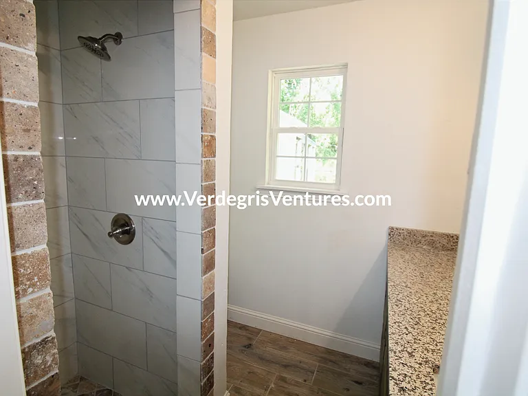 Principal bathroom: This private bathroom includes a stall shower, granite counters, and a porcelain sink, illuminated by warm west_facing natural light