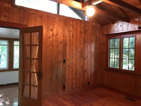 Paneled bedroom with vaulted ceiling with window.