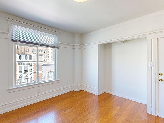 Sunlit room with a large window and wood-like flooring