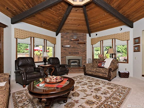 Gorgeous living room with wood-wrapped ceiling leading to a cupola skylight. That's a wood-burning fireplace insert, too. 