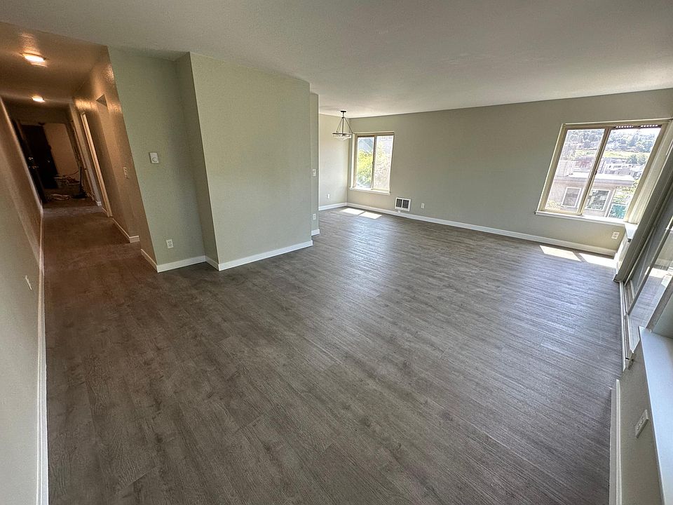 Large living room with balcony and dining room area. West facing balcony and windows and south facing windows in the living and dining area.