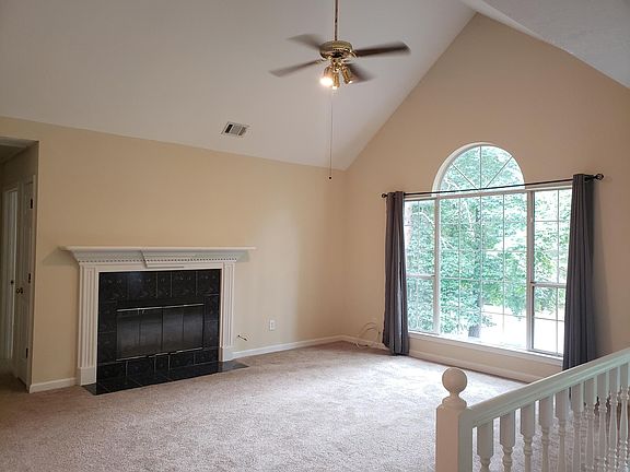 Living room with vaulted ceiling and marble gas starting, wood burning fireplace.