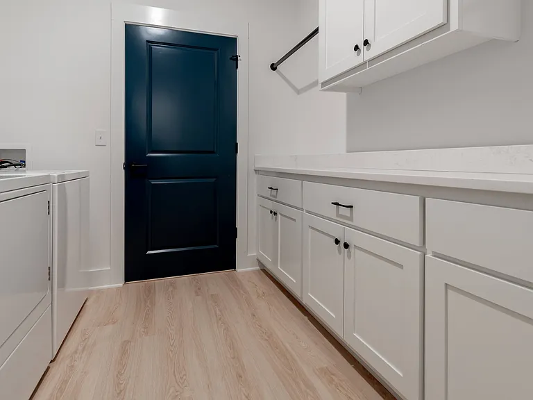 Oversized laundry room with extra storage and hanging rods in the basement.