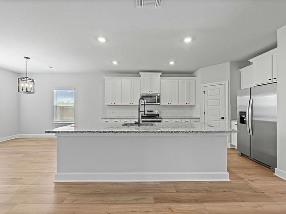 The kitchen has beauitful white cabinetry.