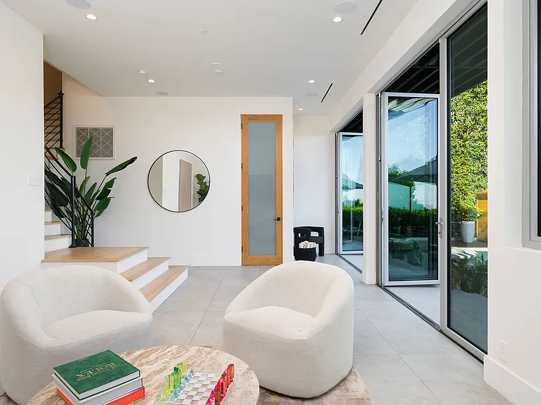 The downstairs lounge features floor-to-ceiling windows that open to the pool, an oversized smart TV, plush seating for four, and a curated selection of board games_perfect for family fun and relaxed evenings together.