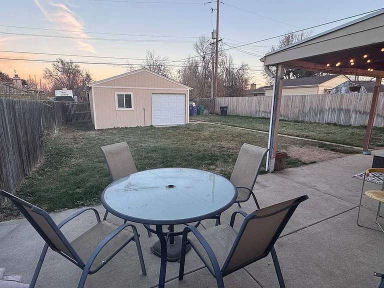 Mature lawn with sprinkler system in fenced backyard.