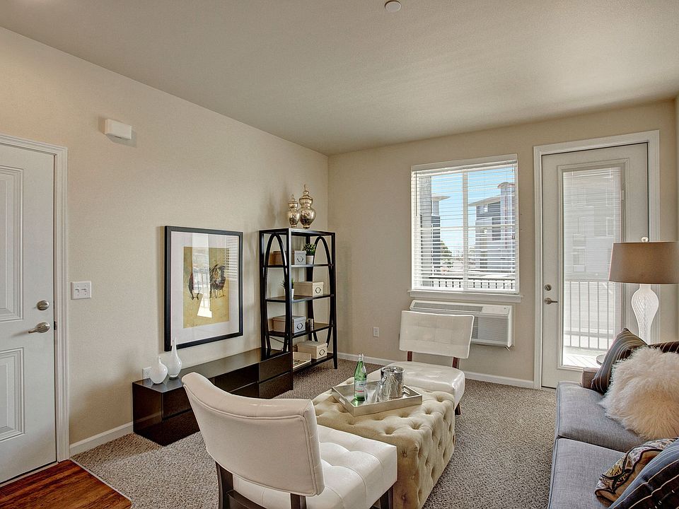 A cozy living room with a large window looking out to the property and access to the private patio