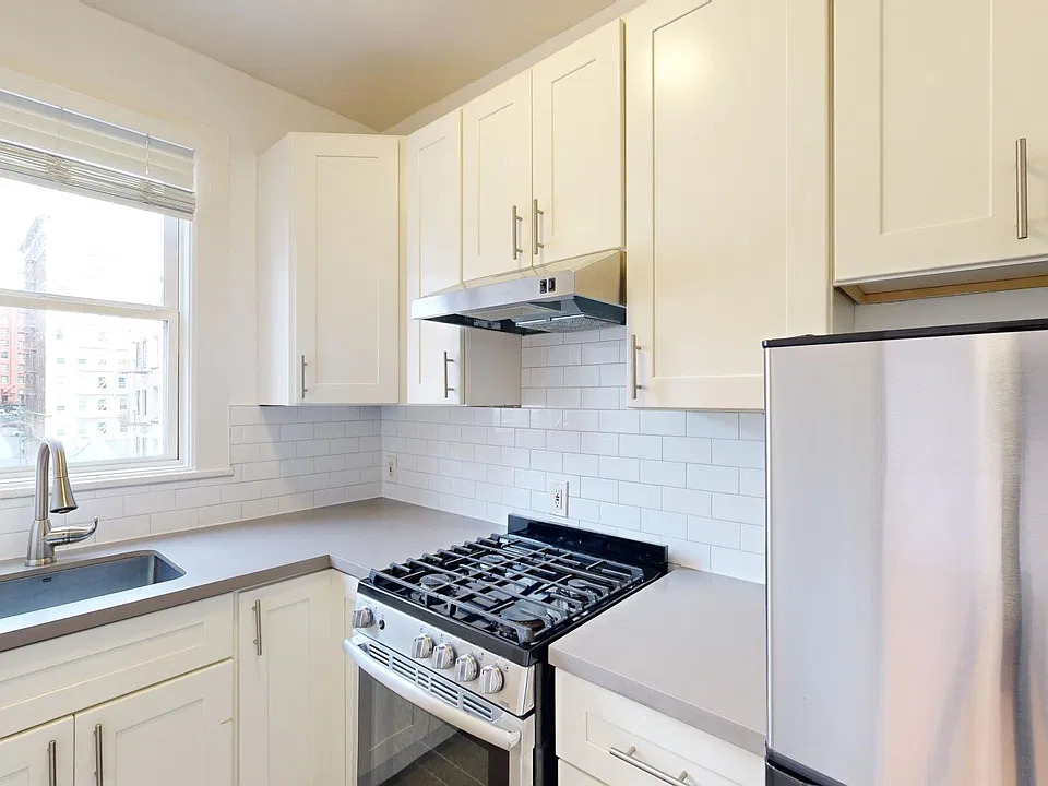 Kitchen with multiple cabinets, refrigerator, stove, range hood, and sink