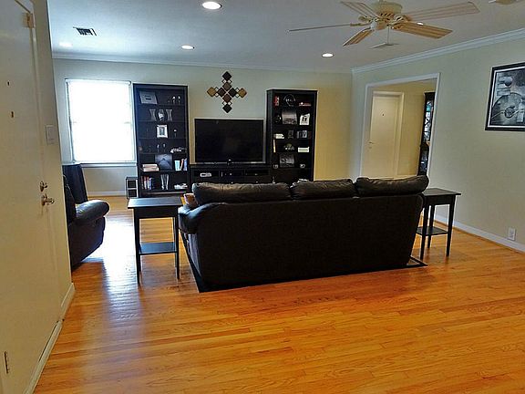 View of the living room from the front door. Crown molding and recessed lighting add an elegant touch.