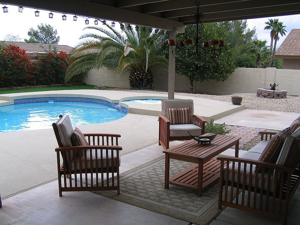 Large covered patio in lush backyard with sparkling pool and spa