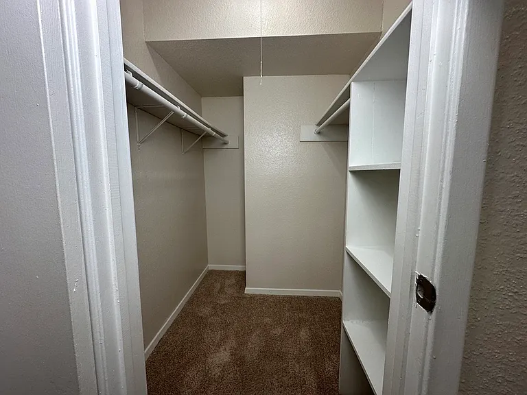 Spacious walk-in closet with built-in shelving and carpet, ideal for organized storage in a modern apartment. Spacious walk-in closet with built-in shelving and carpet, ideal for organized storage in a modern apartment.