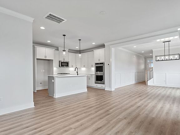 The kitchen open to the great room and dining room of the Mason at Wendell Falls by Brookfield Resid