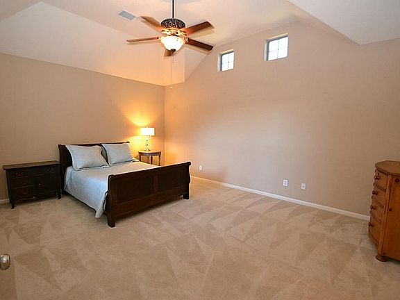 Master bedroom complimented by raised ceilings and a ceiling fan with light fixture.