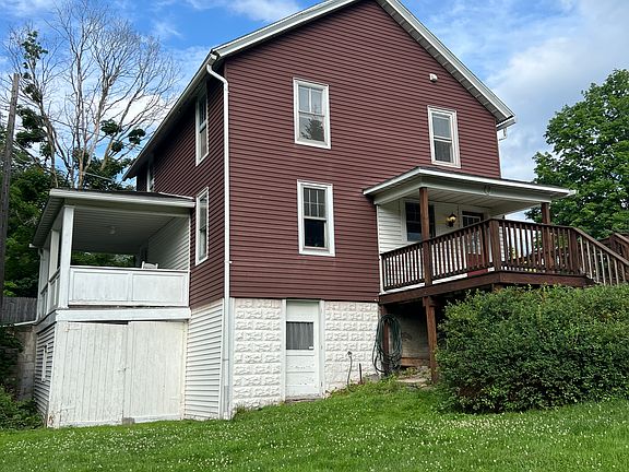 Back of house showing back deck, front porch, walk-out basement, and attached shed with storage