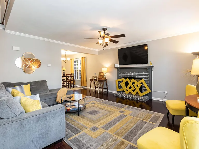 Spacious living room with sectional seating, ceiling fan, and fireplace focal point, plus an adjoining dining nook.