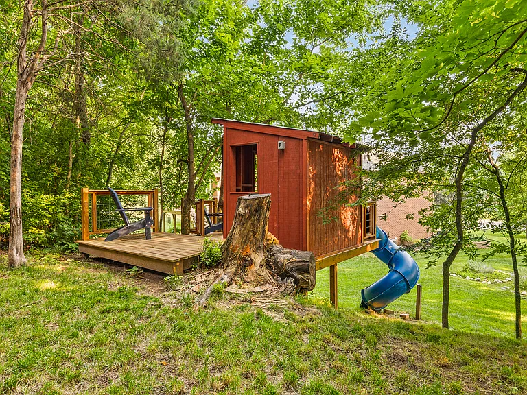 Awesome treehouse with a slide and patio for the kids to get outside and play in the backyard.