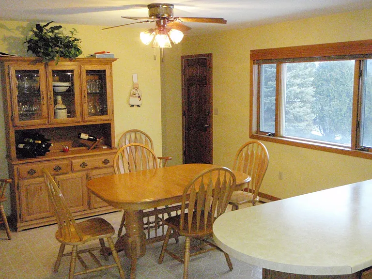 View of the dinning area with another large set of windows (south facing). Backdoor leading to small private patio area. 
Door to basement stairs located opposite back door.