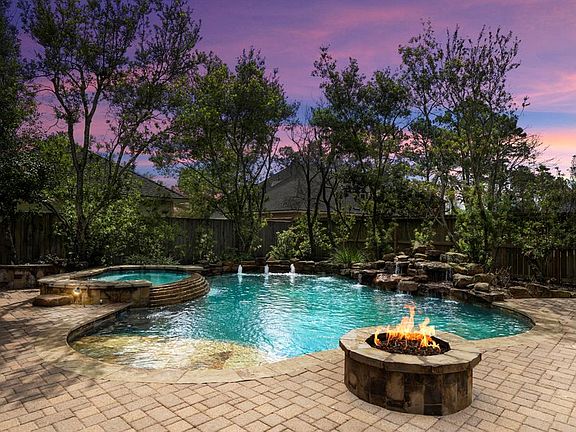 The back of 1714 Meirwoods Drive, with gorgeous sparkling pool, spa, rock waterfall, firepit surrounded by beautiful landscaping.