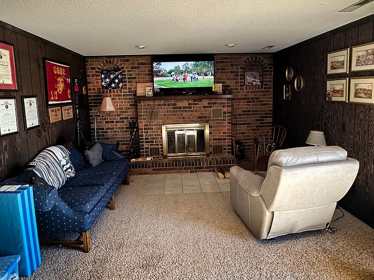 The lower-level family room features a cozy wood-burning fireplace and offers the perfect space for a large big-screen television and comfortable seating. Sliding glass doors open onto a private patio.