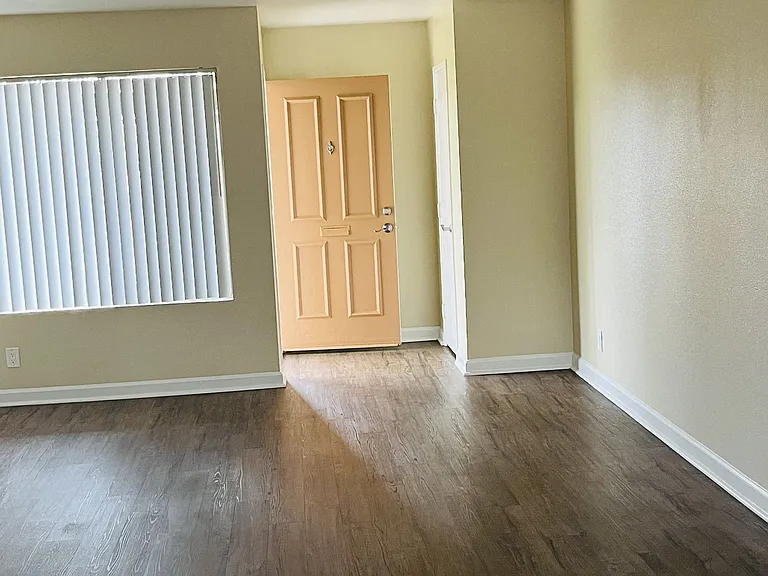 Living room with large window and entry closet with plank style flooring at Plaza Verde Apartments in Escondido, California.
