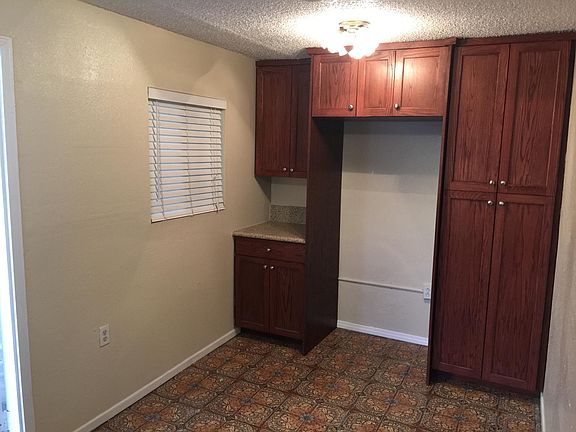 Opening for Refrigerator with Many Built in Cabinets and Pantry. Also Blinds on the window.