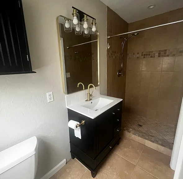 Primary Bathroom: Vanity, sink, faucet, mirrror, light, above the toilet storage, Shower.