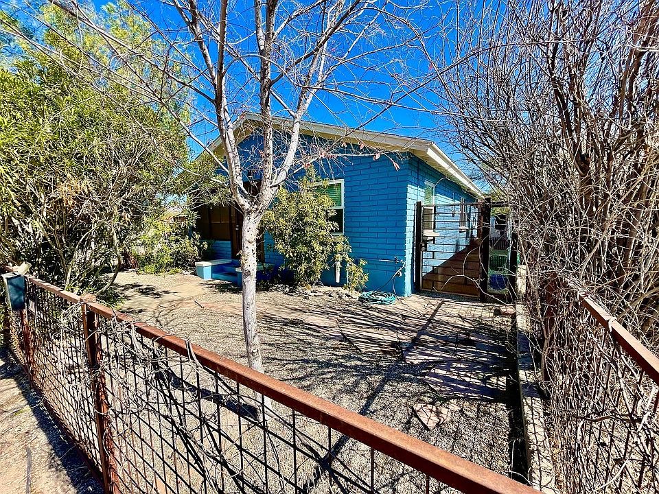 Fenced front yard with mature oleanders, elm, flowering bushes, pomegranate trees.