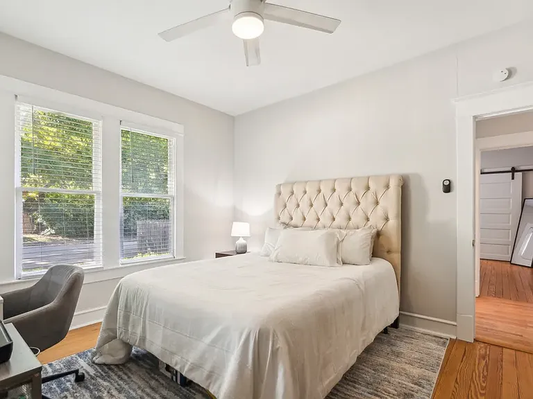 Second bedroom with view back into the hallway and into the primary bedroom. Windows open up to the side yard on Hawthorne Ave