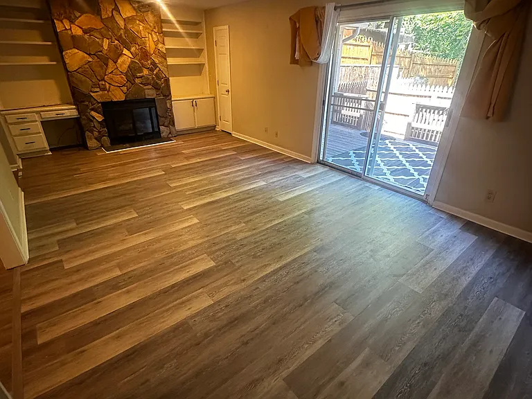 Expansive living room featuring brand-new flooring, a cozy fireplace, and views of the private fenced deck.