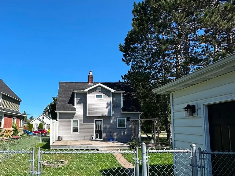 Large fenced in backyard with large deck and fire pit for entertaining.