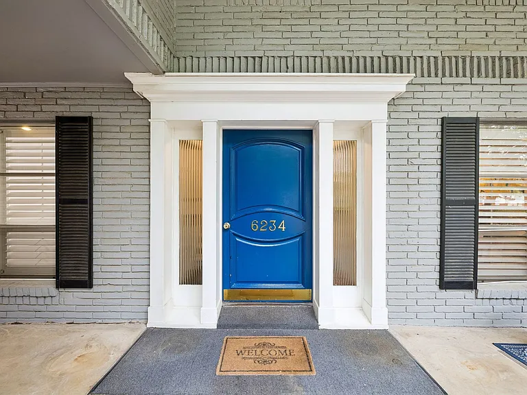 Exterior featuring a vibrant blue entry door, white door frame with sidelights, and gray brick facade