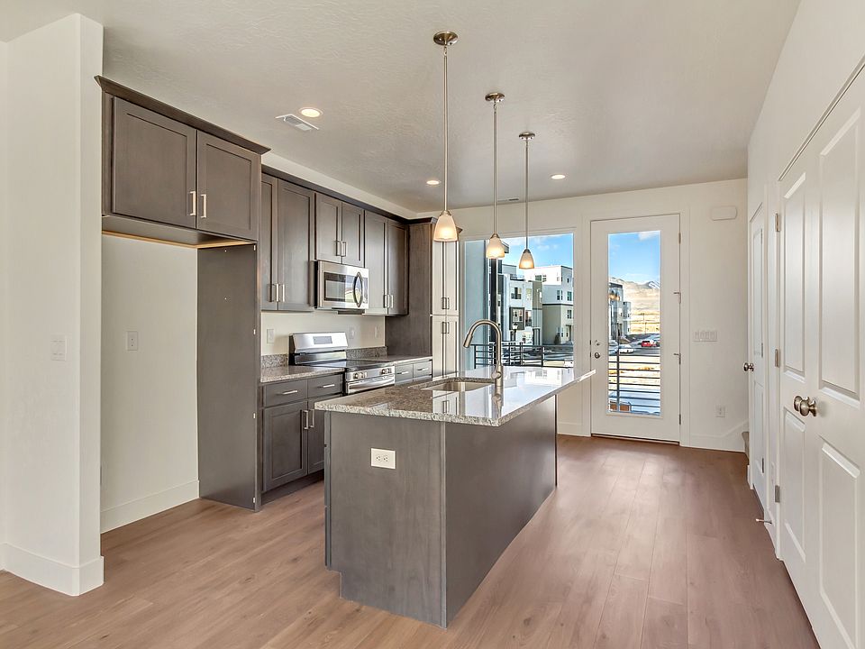 Modern kitchen with dark cabinets, island, pendant lights, and a view of a balcony through glass doo